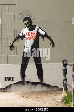 Spray painted graffiti of a zombie, offering free hugs,  on a wall near a canal in Amsterdam Holland. Stock Photo