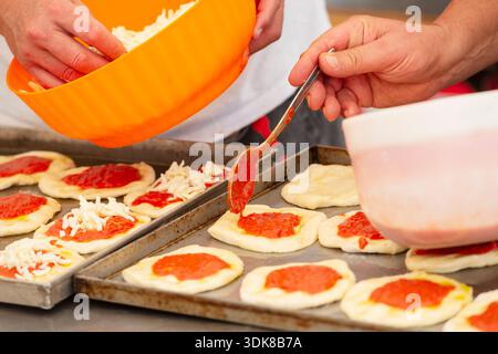 Italy, Chef Preparing Small Pizzas On Baking Sheet In Bakery Stock Photo