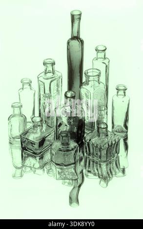 Pleasant arrangement of vintage or antique glass bottles (including inkwells etc) of varying sizes with bottles reflected on surface below. Stock Photo