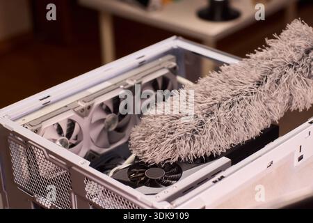 Cleaning computer components with brush. Closeup of dusty electronics being cleaned. Detailed shot of technician cleaning dust from motherboard and Stock Photo