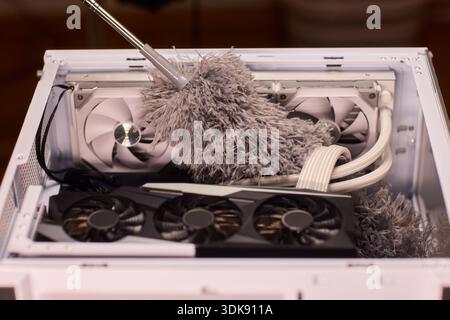 Cleaning computer components with brush. Closeup of dusty electronics being cleaned. Detailed shot of technician cleaning dust from motherboard and Stock Photo