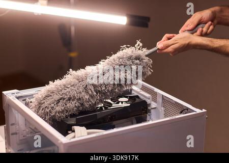 Cleaning computer components with brush. Closeup of dusty electronics being cleaned. Detailed shot of technician cleaning dust from motherboard and Stock Photo