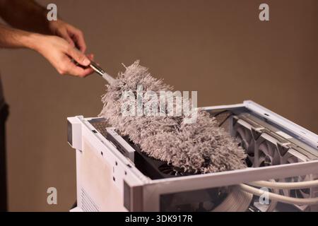 Cleaning computer components with brush. Closeup of dusty electronics being cleaned. Detailed shot of technician cleaning dust from motherboard and Stock Photo