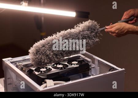 Cleaning computer components with brush. Closeup of dusty electronics being cleaned. Detailed shot of technician cleaning dust from motherboard and Stock Photo