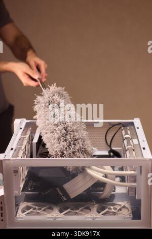Cleaning computer components with brush. Closeup of dusty electronics being cleaned. Detailed shot of technician cleaning dust from motherboard and Stock Photo