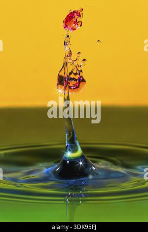 Drops of water with bright colors on a yellow background, splashing and dynamic, high-speed photography, snapshot, water droplets, water figures, conc Stock Photo