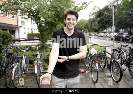 Joyful man scratching his itching arm while smiling broadly in front of parked bicycles in city, showcasing a cheerful mood, being open-minded full of Stock Photo