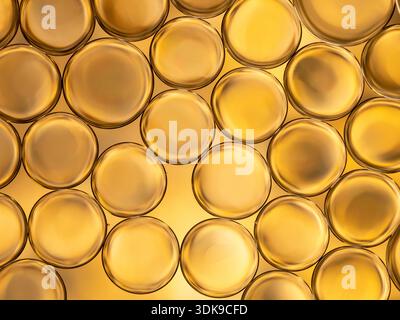 Macro shot of overlapping golden circular bubbles glowing under warm light. Smooth surfaces and soft reflections create an abstract, luxurious mood su Stock Photo