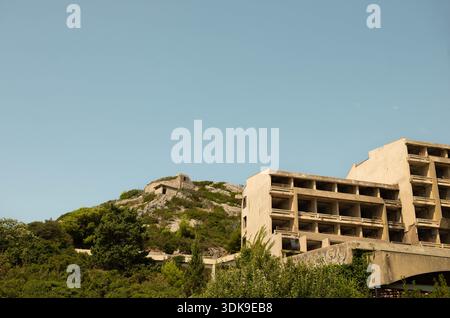 KUPARI, CROATIA - JULY 29, 2024: Ruined brutalist hotel with a military bunker on the hill above. Destroyed concrete blocks from the 1990s war Stock Photo