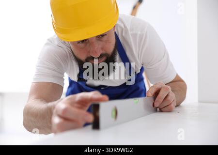 Worker measuring white dresser with building level indoors Stock Photo