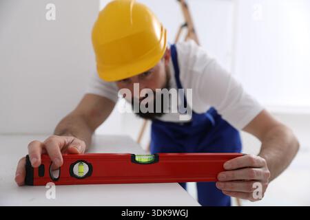 Worker measuring white dresser with building level indoors, selective focus Stock Photo