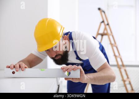 Worker measuring white dresser with building level indoors, selective focus Stock Photo