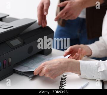 Office workers using printer at white desk indoors, closeup Stock Photo