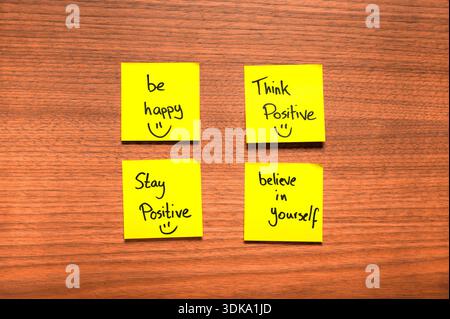 Four yellow sticky notes arranged in a 2x2 grid on a wooden surface, each featuring a handwritten motivational message in black marker. Phrases like " Stock Photo