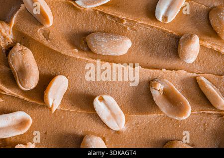 Shelled peanuts scattered on a background of creamy peanut butter Stock Photo