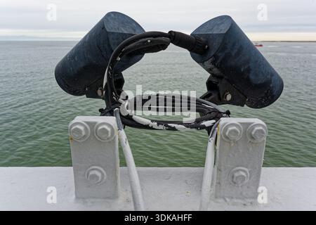 Two elongated black cameras are mounted facing different directions, with the sea behind them, suggesting wide monitoring coverage on a ship deck duri Stock Photo