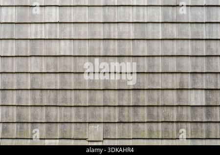 Full frame background texture of regular gray rectangular slate tiles on a building roof or wall, architectural pattern. Stock Photo