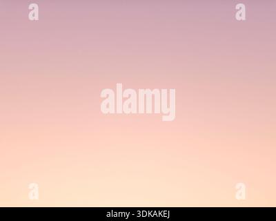 Minimalist nature background of a clear sky with soft pastel gradient color transition from pink to orange during sunset or dawn. Stock Photo