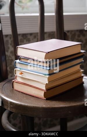 Stack of old books on a wood chair Stock Photo