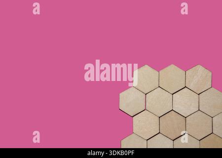 Hexagon wooden tiles creating a honeycomb pattern on a bright pink background Stock Photo