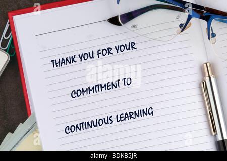 A white lined notebook page features a thank you message for continuous learning. Blue reading glasses rest on the top and a silver pen lies at the bo Stock Photo