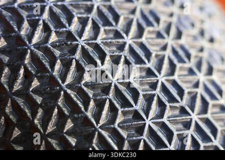 Macro shot of black geometric pattern texture. abstract industrial surface creates strong, detailed background with complex grip. design feels technic Stock Photo