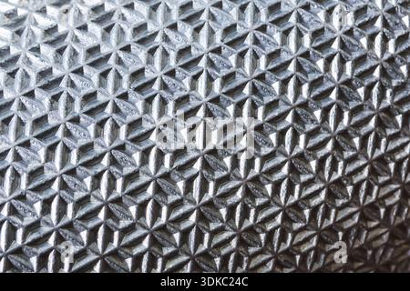 Detailed macro background of textured silver metal surface with repeating geometric pattern. This abstract, industrial material has tough, sleek, and Stock Photo