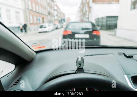 View from inside a car showing the dashboard with a small camera and a vehicle ahead on a city street. Concept of driving technology, navigation. Stock Photo