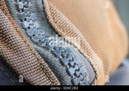 Close up macro detail of grey zipper on brown textile fabric. functional element of clothing and fashion, this shows texture and connection of fastene Stock Photo