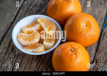 several oranges fruit and slices in a white plate on an old wooden table Stock Photo