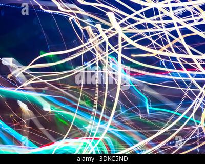 Intersecting and intertwining light streaks in white, blue, green, and red hues generating a dynamic visual representation of energy, movement, and te Stock Photo