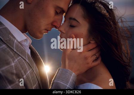 A bride and groom share an intimate moment during their wedding ceremony with a soft sunset glow Stock Photo