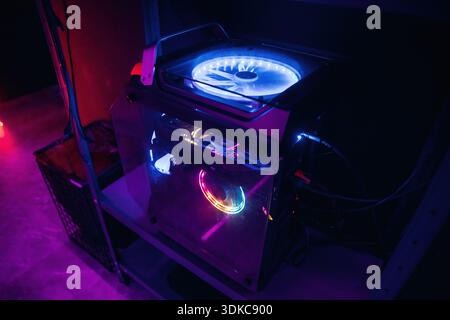 Powerful gaming computer with colorful cooling system in dark room. Stock Photo