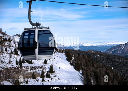 Cable car gondola above a snowy alpine landscape with ski slopes