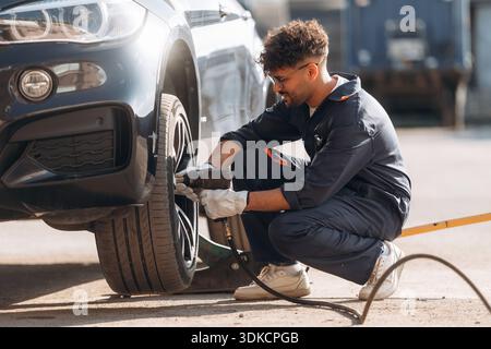 Process of changing the tire. Mechanic is with the car outdoors. Stock Photo
