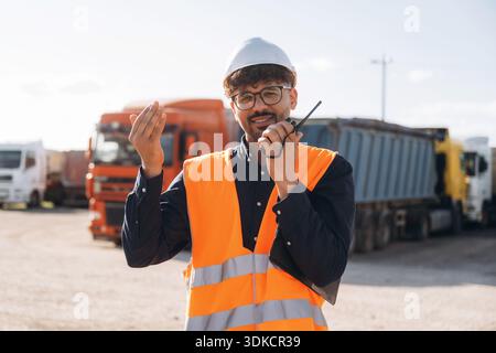 Conversation by using walkie talkie. Male worker is near truck outdoors. Stock Photo