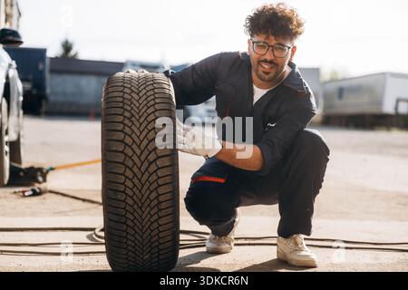 Looking forward, with tire. Mechanic is with the car outdoors. Stock Photo