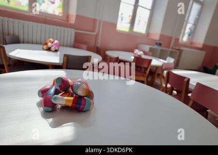 Colorful wooden bowling pins in mesh bags arranged on tables inside a bright kindergarten or preschool classroom Stock Photo