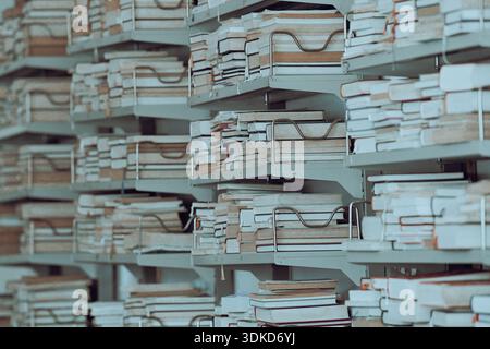 Stacks of old books and documents stored on metal shelves inside a library archive Stock Photo