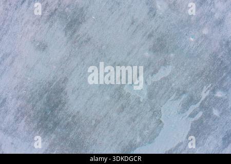 Abstract top view of an irregular frozen surface with mottled ice textures and soft blue tones. Perfect for creative backgrounds that require a natural, slightly weathered winter look. Stock Photo