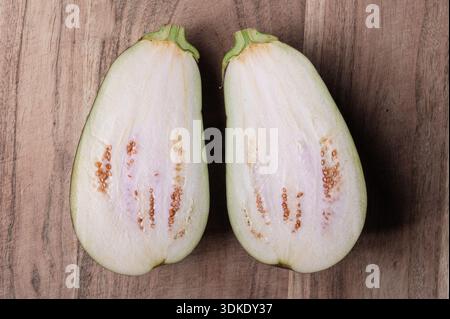 The interion of an eggplant cut in half on a wood cutting board Stock Photo