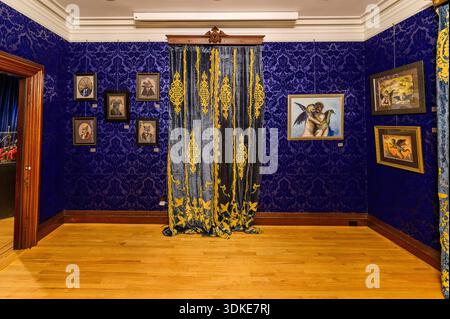 Empty gallery room with framed artwork and blue patterned walls inside the The Satanic Temple headquarters and museum space in Salem, Massachusetts. Stock Photo