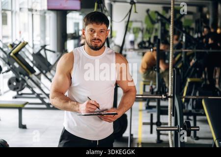 Writing information into notepad. Strong man is working out in the gym. Stock Photo