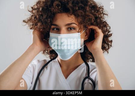 In protective facial mask. Beautiful doctor woman is in the studio. Stock Photo