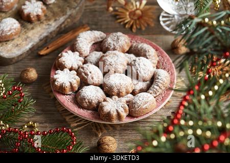 Homemade traditional Czech Christmas cookies called pracny on a red plate with spruce tree branches and straw ornaments Stock Photo