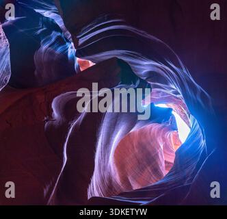 The smooth, undulating sandstone walls of Antelope Canyon in Arizona are illuminated by beams of light filtering down from above, creating a surreal a Stock Photo