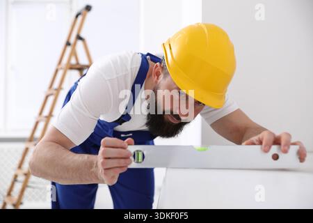 Worker measuring white dresser with building level indoors Stock Photo