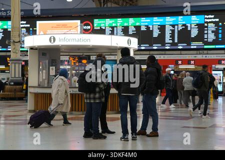 Passengers gathering at the information desk in the concourse of London Victoria station with large departure boards overhead.Victoria station , London Stock Photo