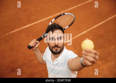 Focused photo on tennis ball in hand. Man is playing tennis indoors in the hangar. Stock Photo