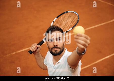 Focused photo on tennis ball in hand. Man is playing tennis indoors in the hangar. Stock Photo